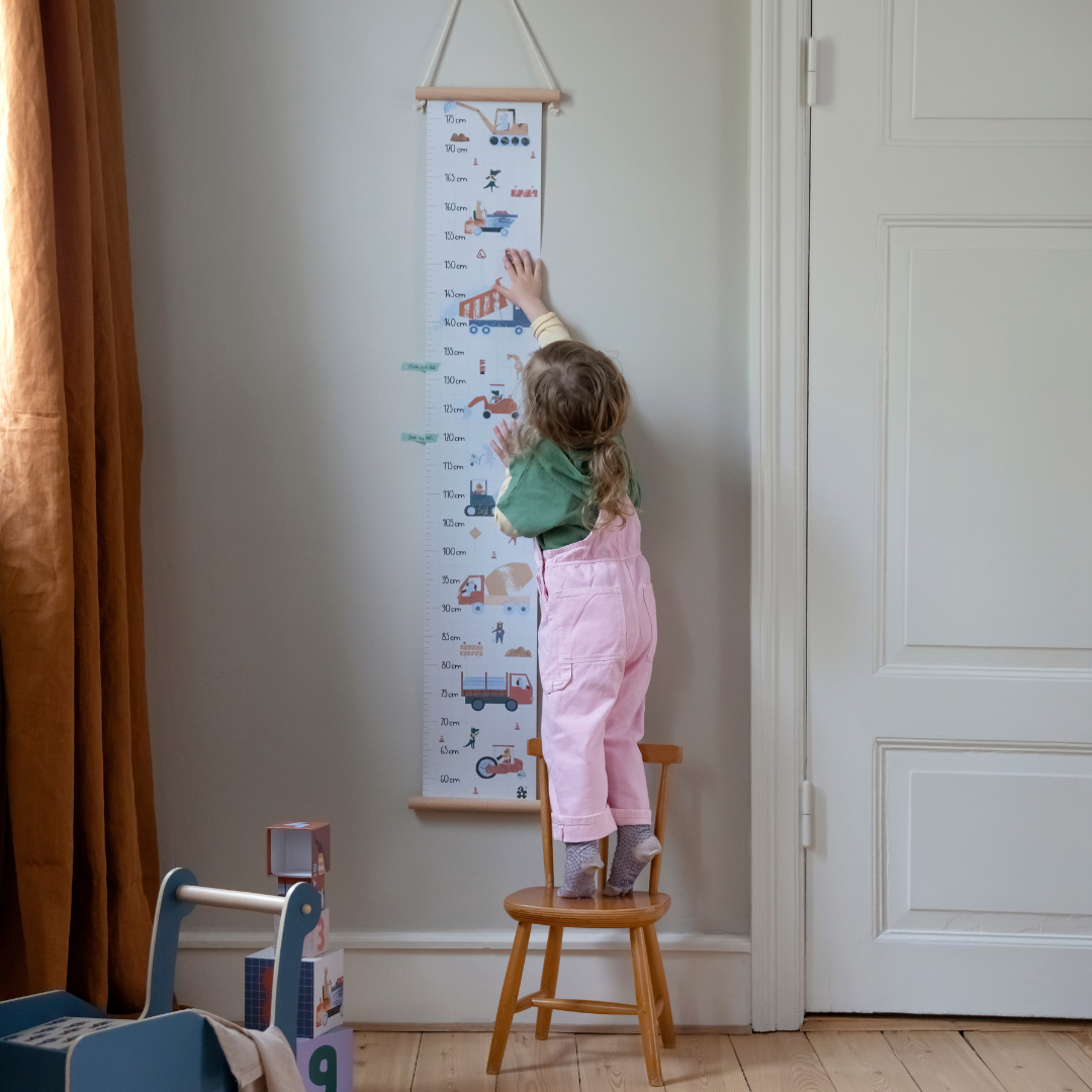 Kislány méretkezik magasságmérő előtt a gyerekszobában széken állva - pippadu - Sebra