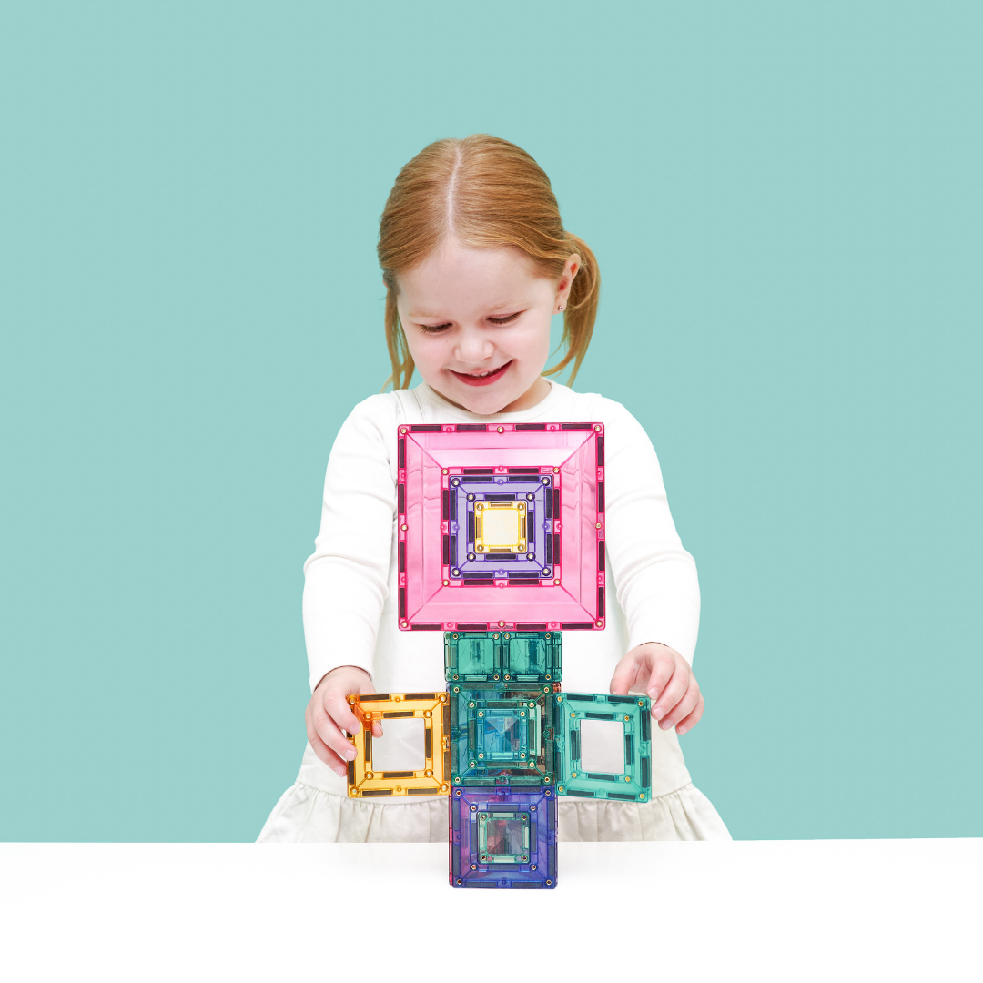 Gyermek épít a Connetix pasztell Portal Pack 48 db mágneses építőjáték átlátszó elemeivel.