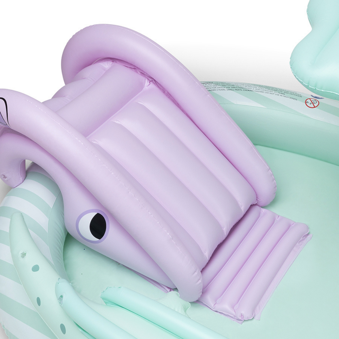 A szafari élménymedencébe épített lila-rózsaszín csíkos felfújható mini csúszda közelről.