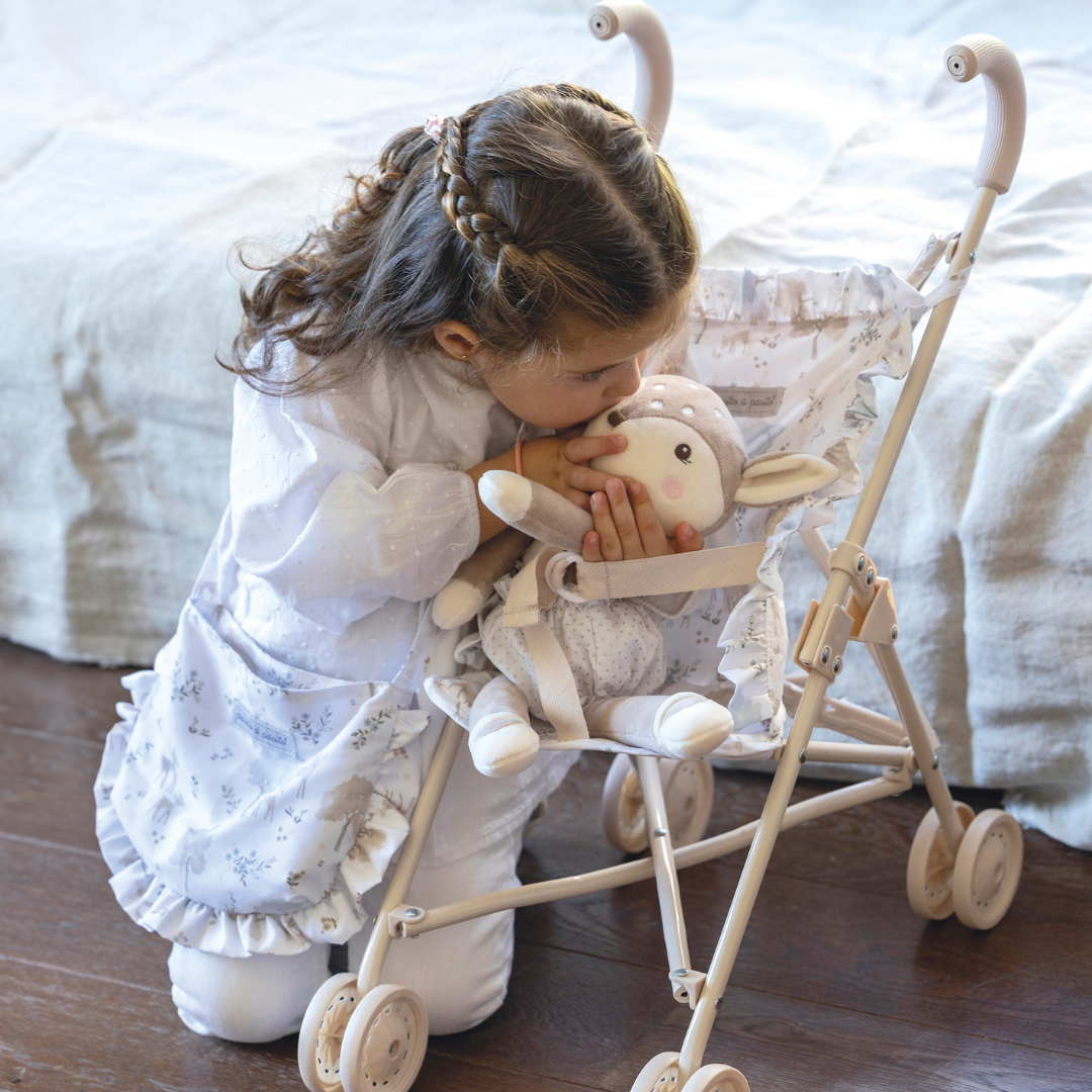 Kislány megpuszilja az őzikét, akit a játék babakocsijában tologat