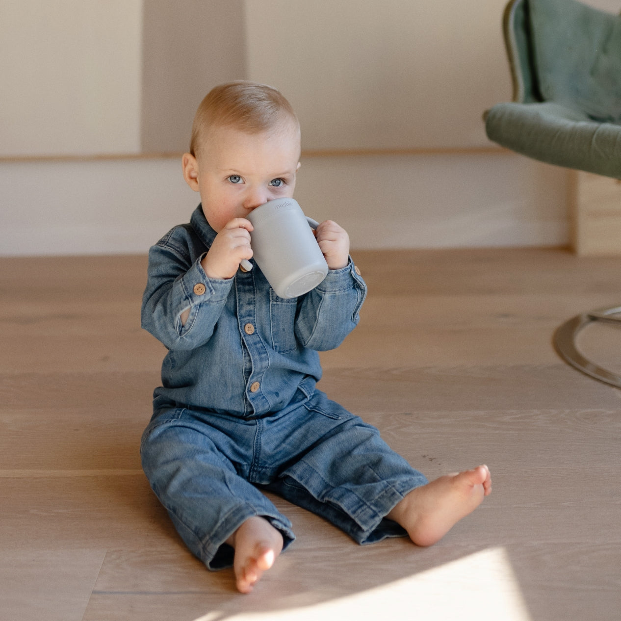 Kisfiú farmer ruhában ülve iszik a mushie tanulópohárból - pippadu