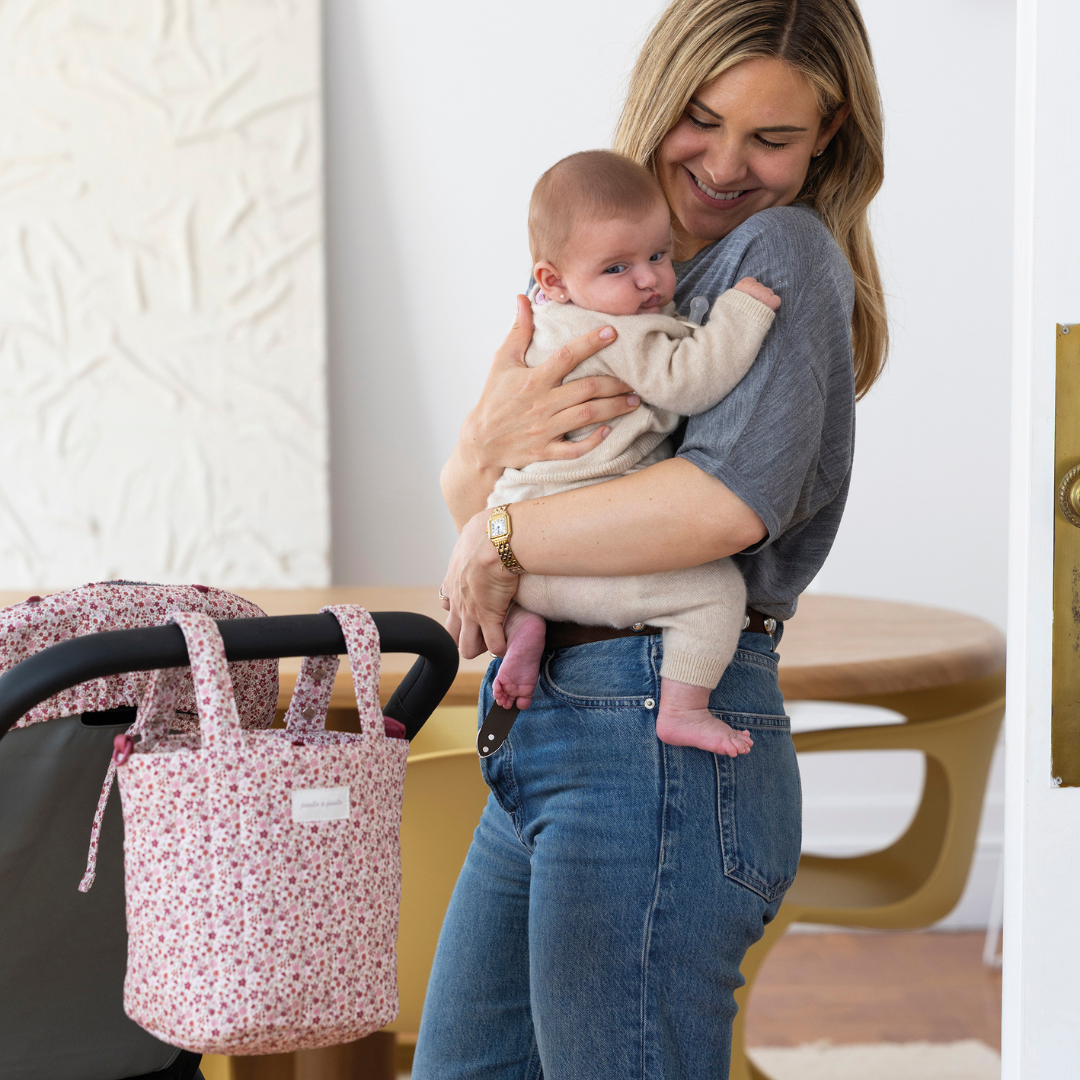 Édesanya nevet kisbabájára, háttérben babakocsin Cherry virágos kézitáska a rövid fülekkel egyszerűen rögzítve