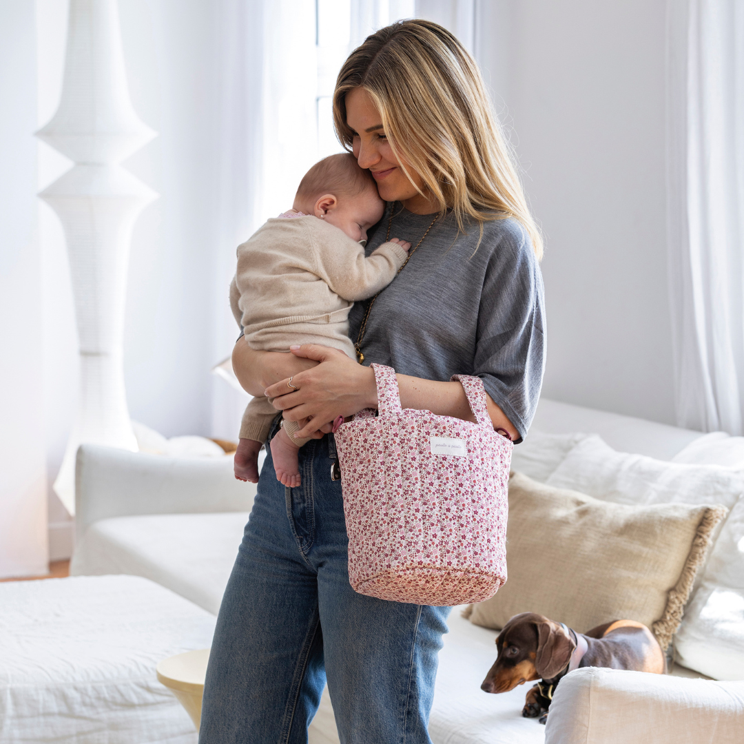 Kisbaba anyukája kezében tacskó a háttérben Az édesanya kezén rövid fülekkel Cherry virágos kézitáska a Pasito a Pasito márkától