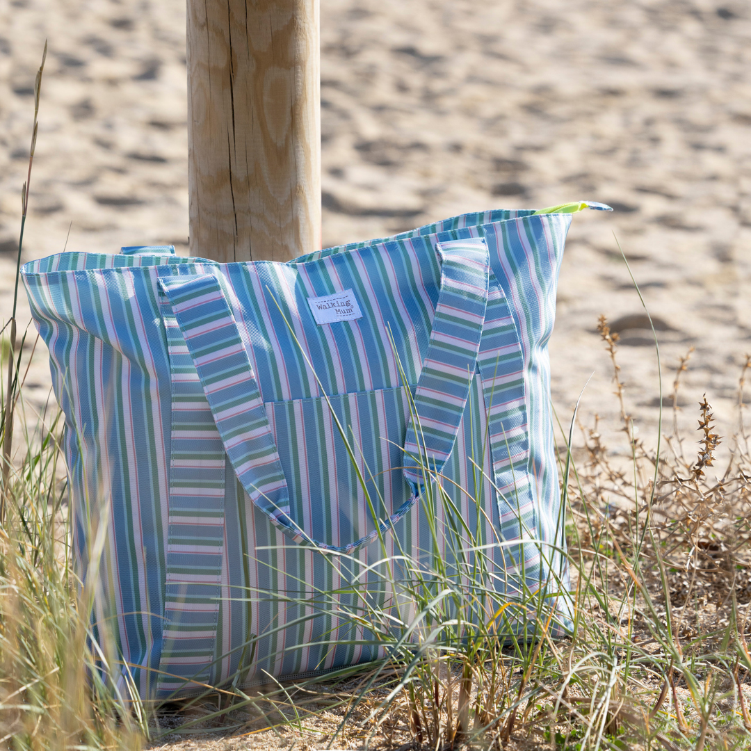 Csíkos mintás strandtáska a homokos tengerparton egy faoszlop mellett a homokban