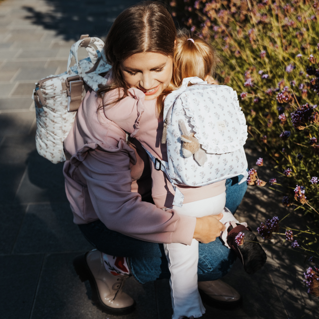Virágos gyerek hátizsák fodros részletekkel, aranyos állatos kiegészítővel - kislány és anyukája összeillő pulóverben és hátizsákban a Városligetben