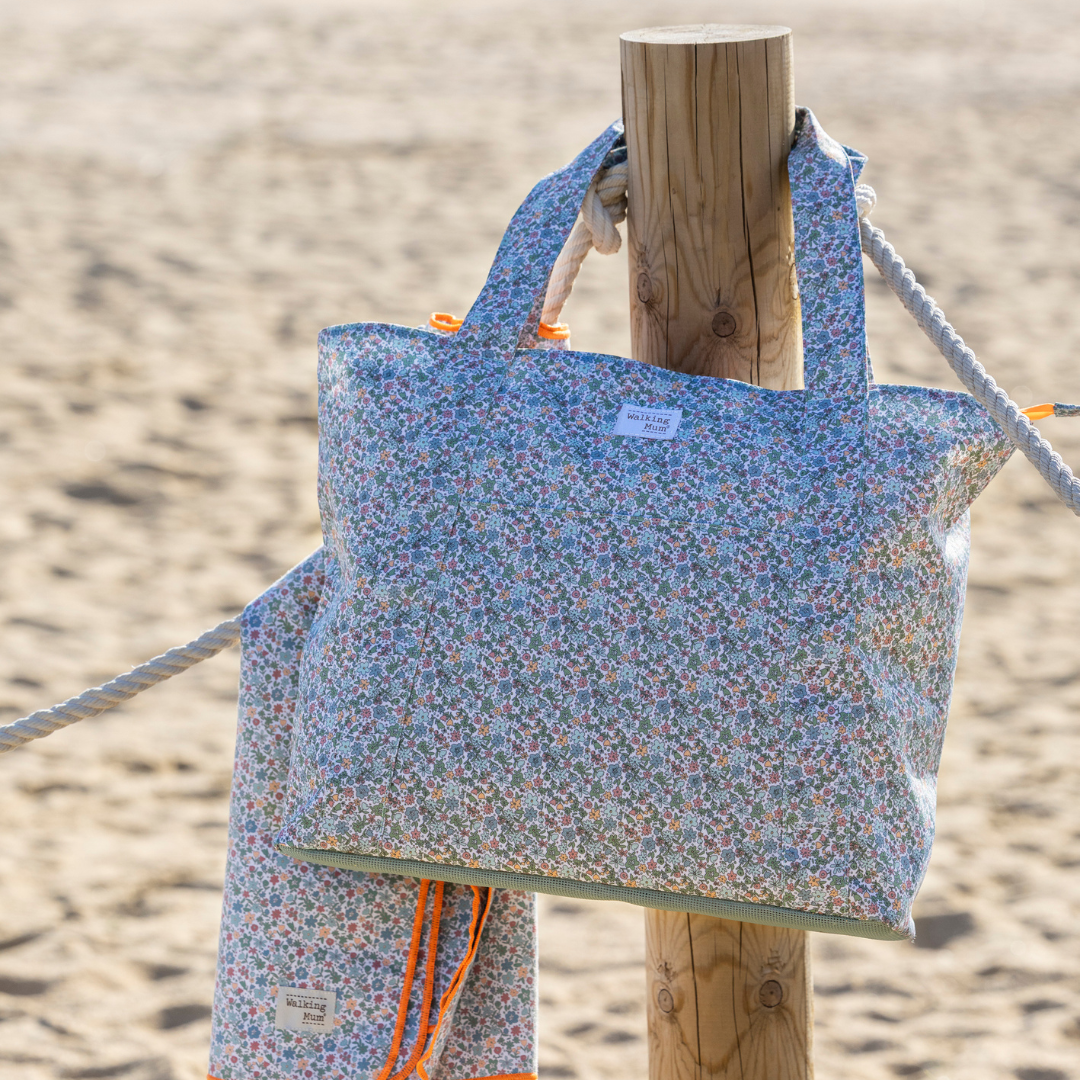 Virágos strandtáska a homokos parton egy faoszlopra akasztva