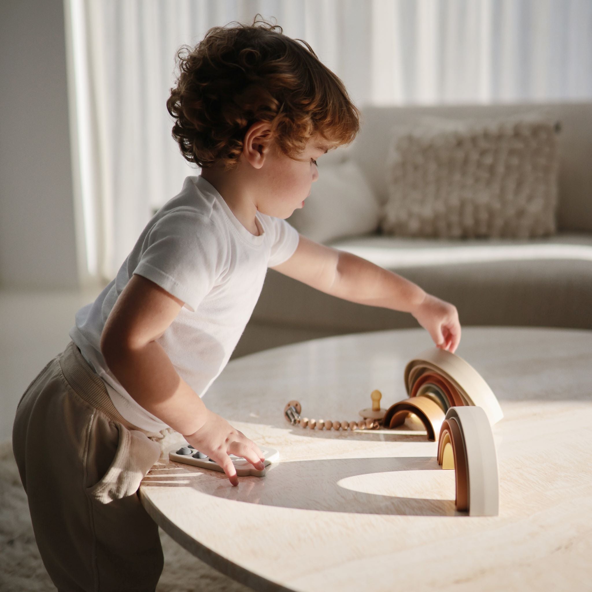 Napsugár színekben pompázó szivárvány építő játék a Mushie márkától - pippadu