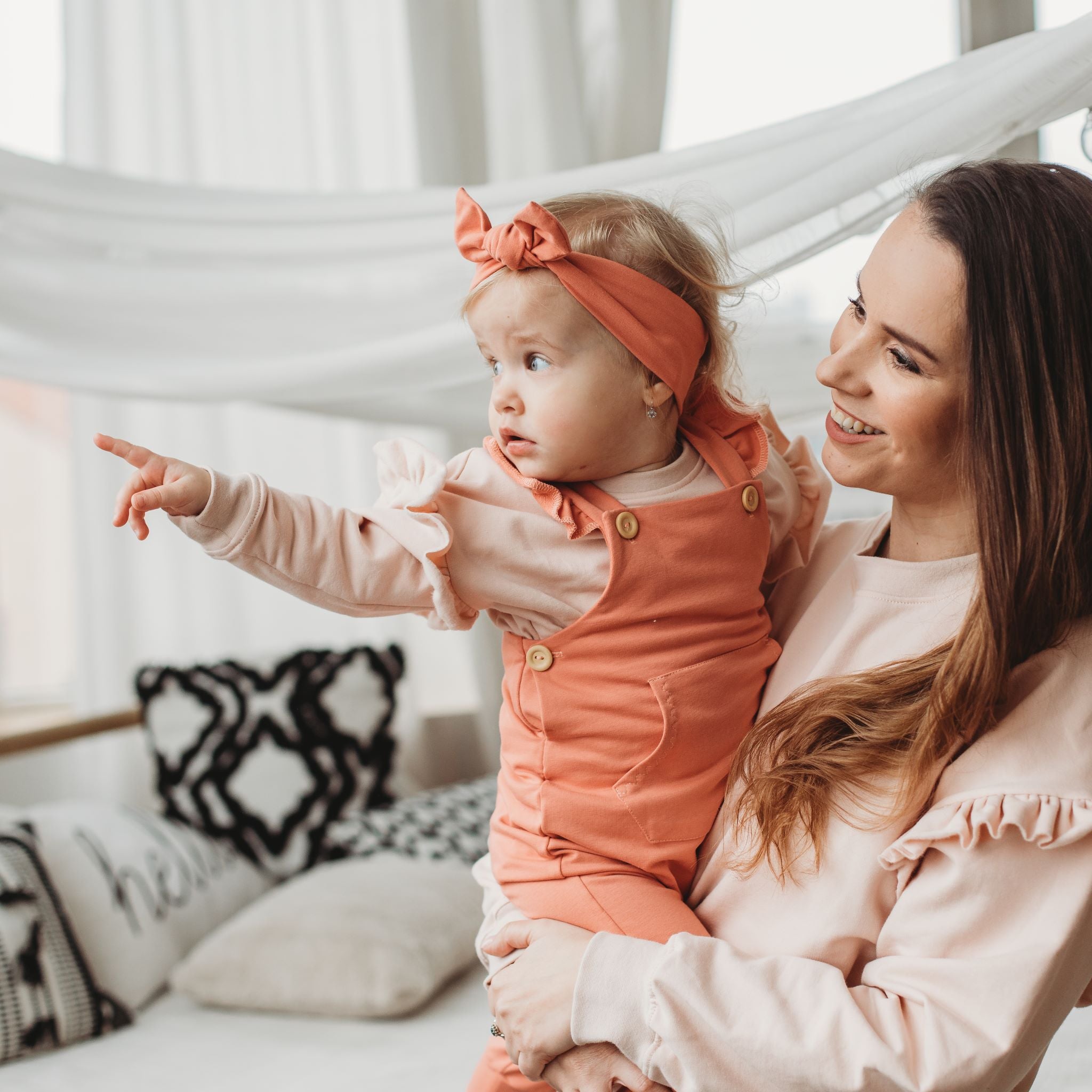 Kislány édesanyja kezében oldalra mutat hamvas púder fodros pulóverben - pippadu