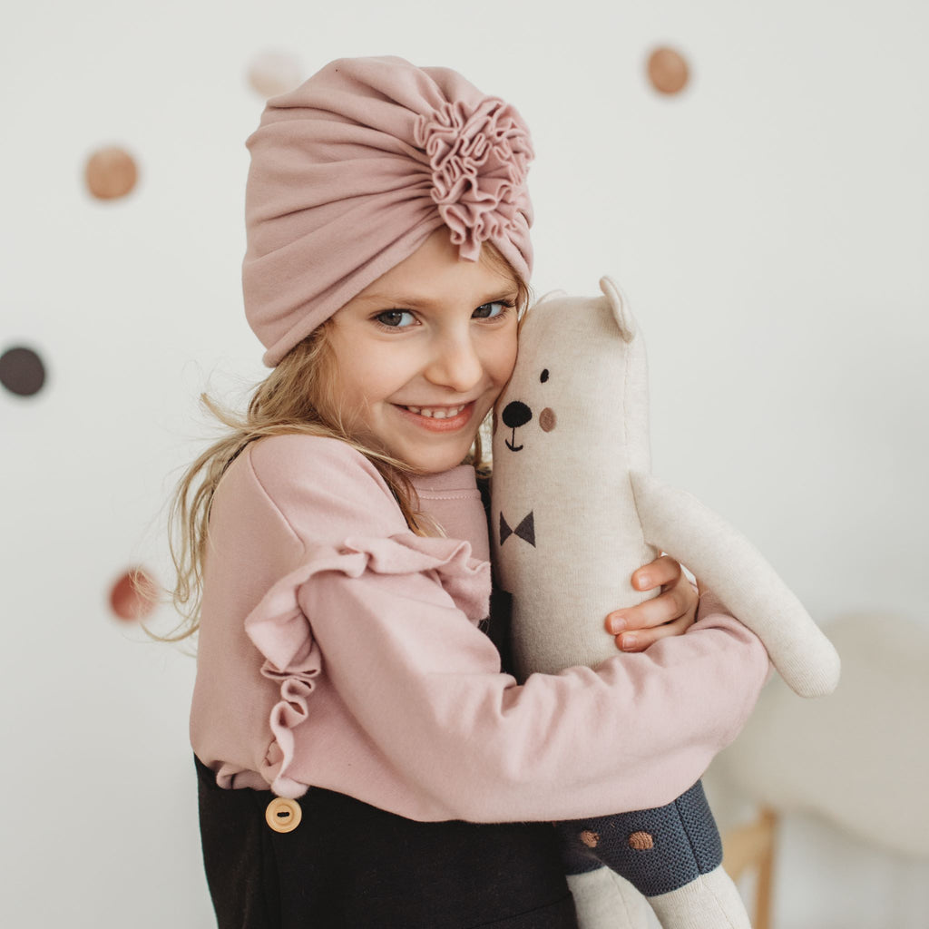 Kislány plüss mackót ölel szilvarózsa turbánkában és fodros pulóverben - pippadu