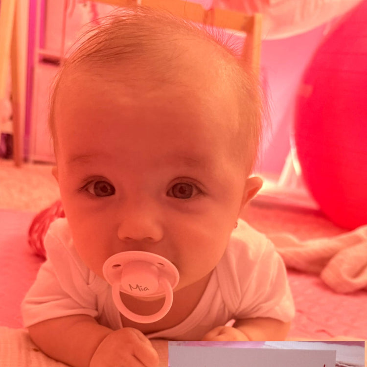 Kislány BIBs De Lux nevesített cumival a szájában