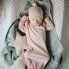 Kisbaba pelenkázón pihen Mushie csillag szundikendővel az oldalán, cumival a szájában