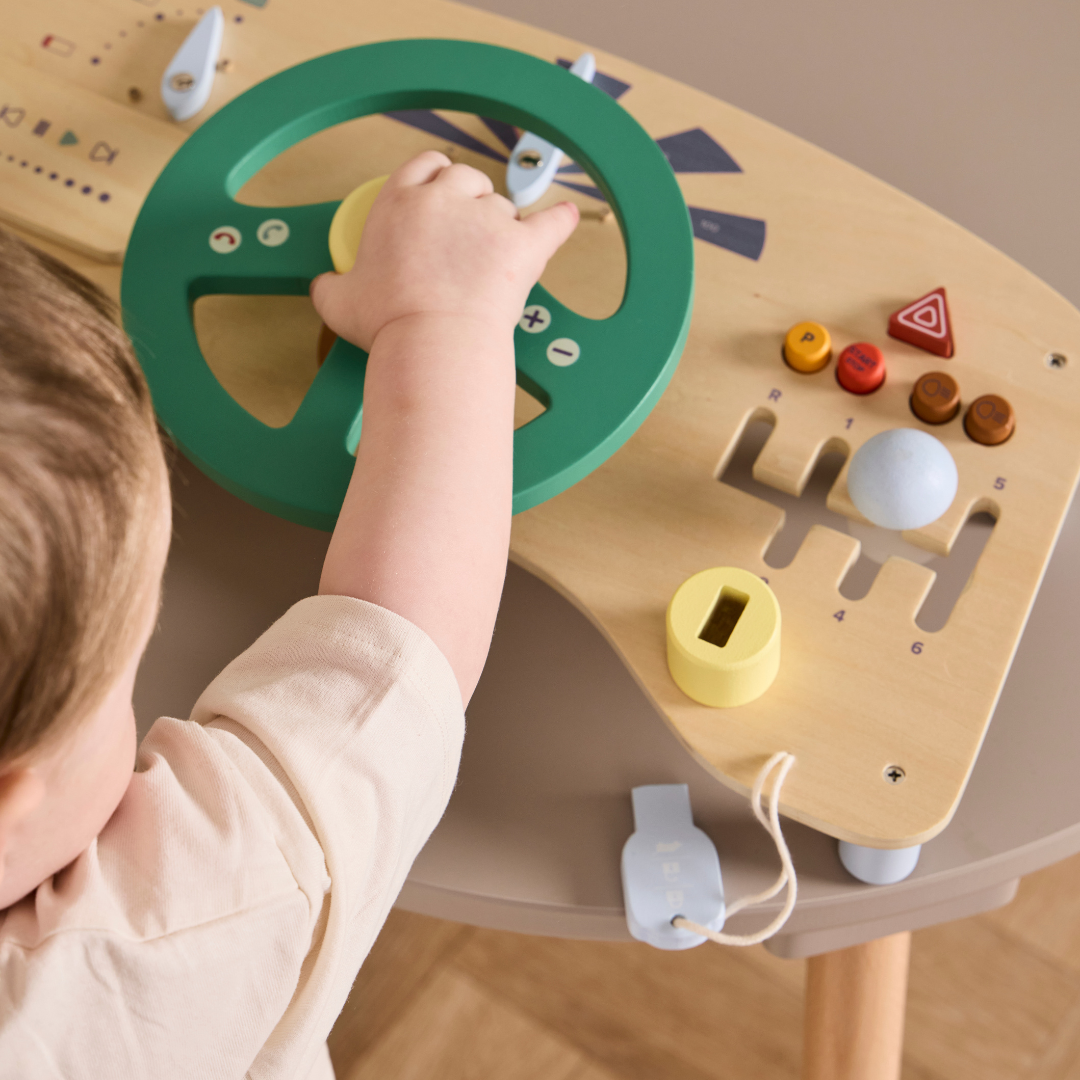 Kisgyermek keze a Kid's Concept autós foglalkoztató tábla kormányán és gombjain