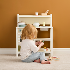 Játék konyha gyerekeknek a Kid's Concept márkától - kisgyerek a konyha előtt ülve játszik az evőeszközökkel