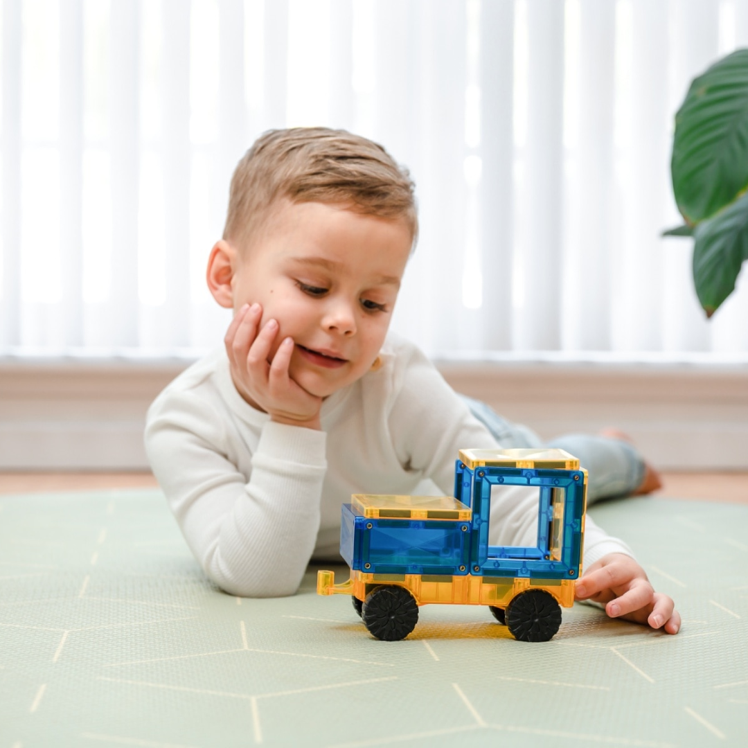 Kisfiú autóval játszik, amit a Connetix autóalappal épített meg, igazi gumikerekekkel