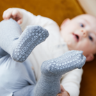 Kisbaba happy baby pózban és GobabyGo csúszásgátlós szürke harisnyanadrágban játszik