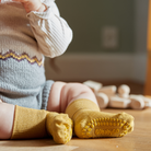 Kisbaba a földön ül csúszásgátlós bambusz zoknival a lábán