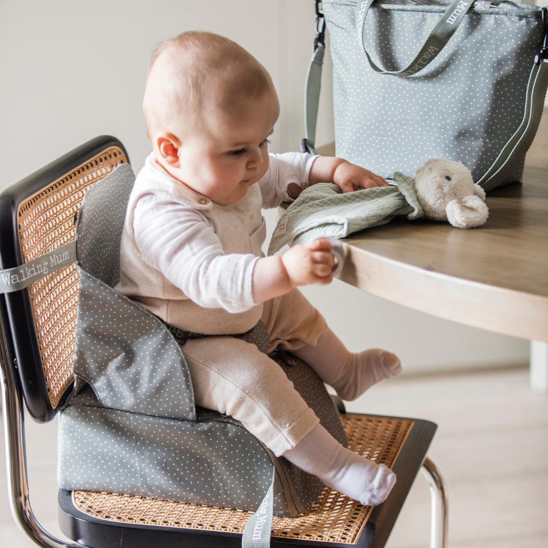 Pottyös oliva textil székmagasító utazáshoz, thonet székre rögzítve, egy étkezőasztalnál ülő kisbabával