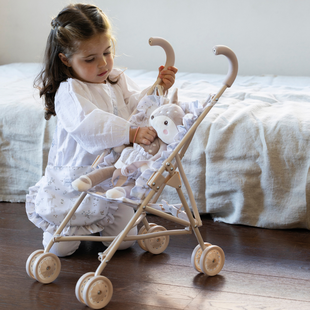 Kislány őzikével és játék babakocsival játszik a gyerekszobában