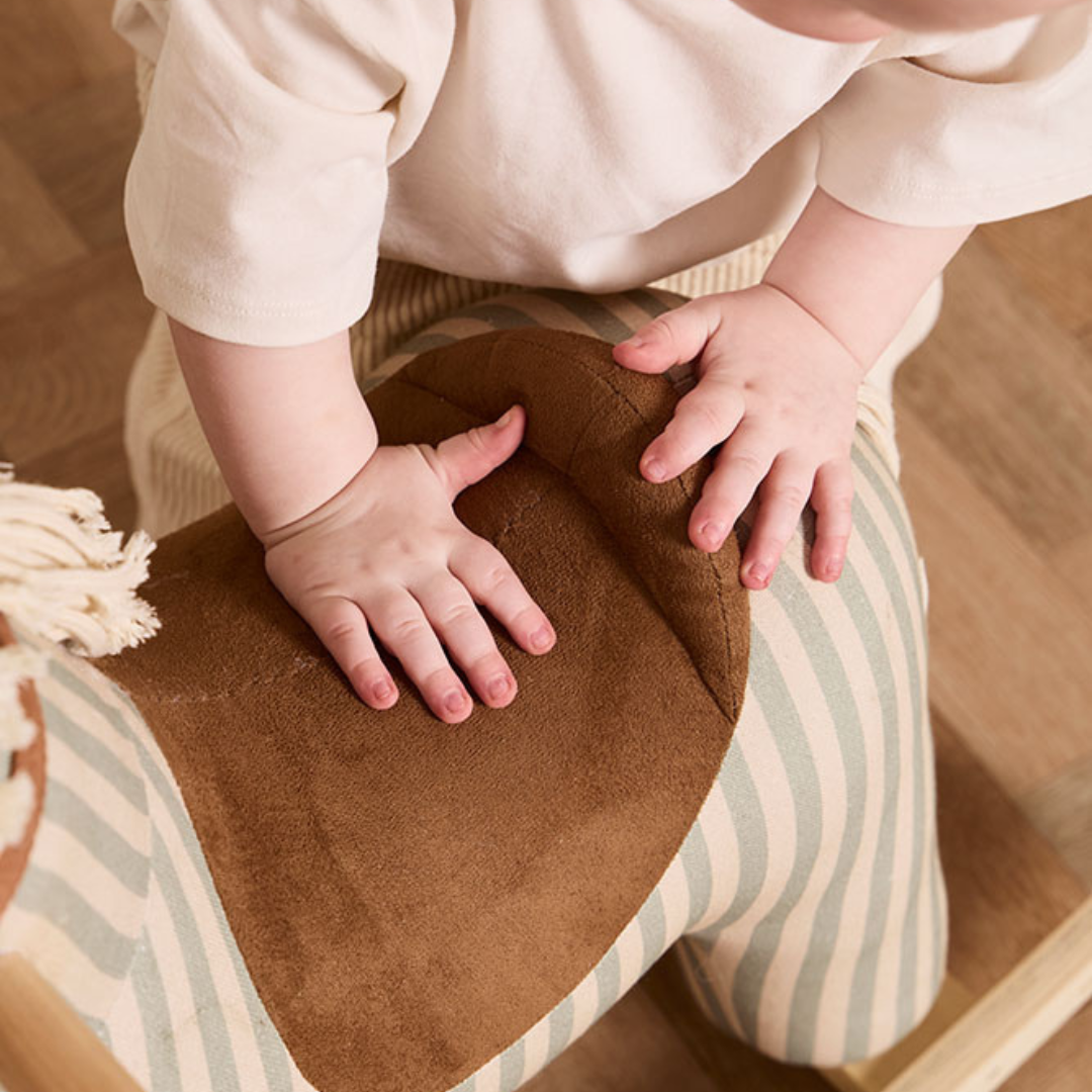 Közelkép a Kid's Concept Sam hintaló barna, puha tapintású nyergéről és a prémium csíkos textil anyagáról