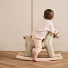 Kisgyermek játszik a Kid's Concept Sam csíkos hintalovon, skandináv stílusú gyerekszobában