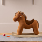 A Kid's Concept Vera barna kordbársony hintaló egy skandináv stílusú gyerekszobában, csíkos szőnyegen állva, játékok mellett a Pippadu kínálatából