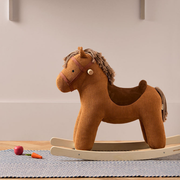 A Kid's Concept Vera barna kordbársony hintaló egy skandináv stílusú gyerekszobában, csíkos szőnyegen állva, játékok mellett a Pippadu kínálatából