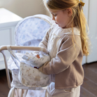 Kislány fodros válltáskába pakol, ami a klasszikus, vintage babakocsihoz illő mintával készült