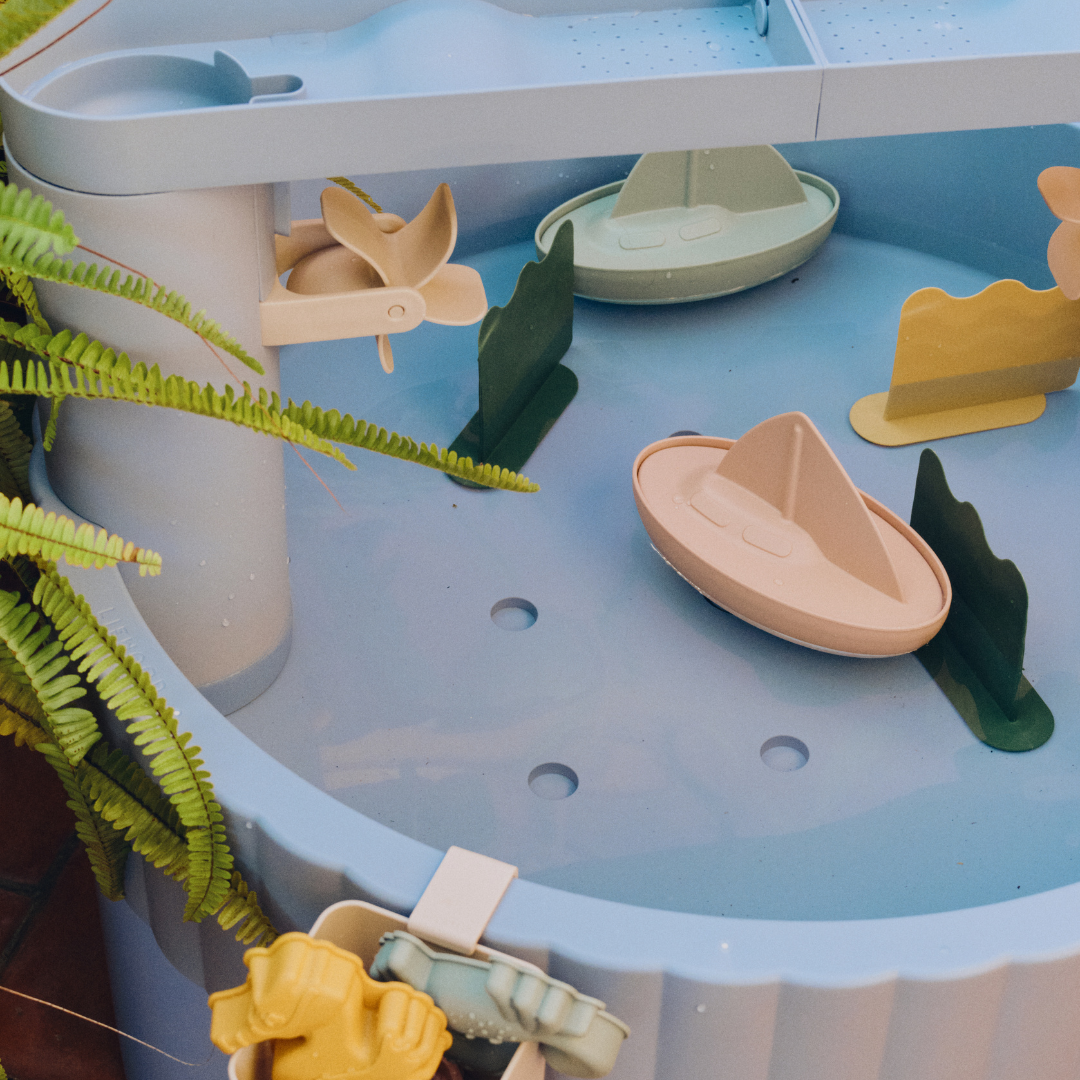 Kék Liewood Sepp játékasztal kültéren növények között