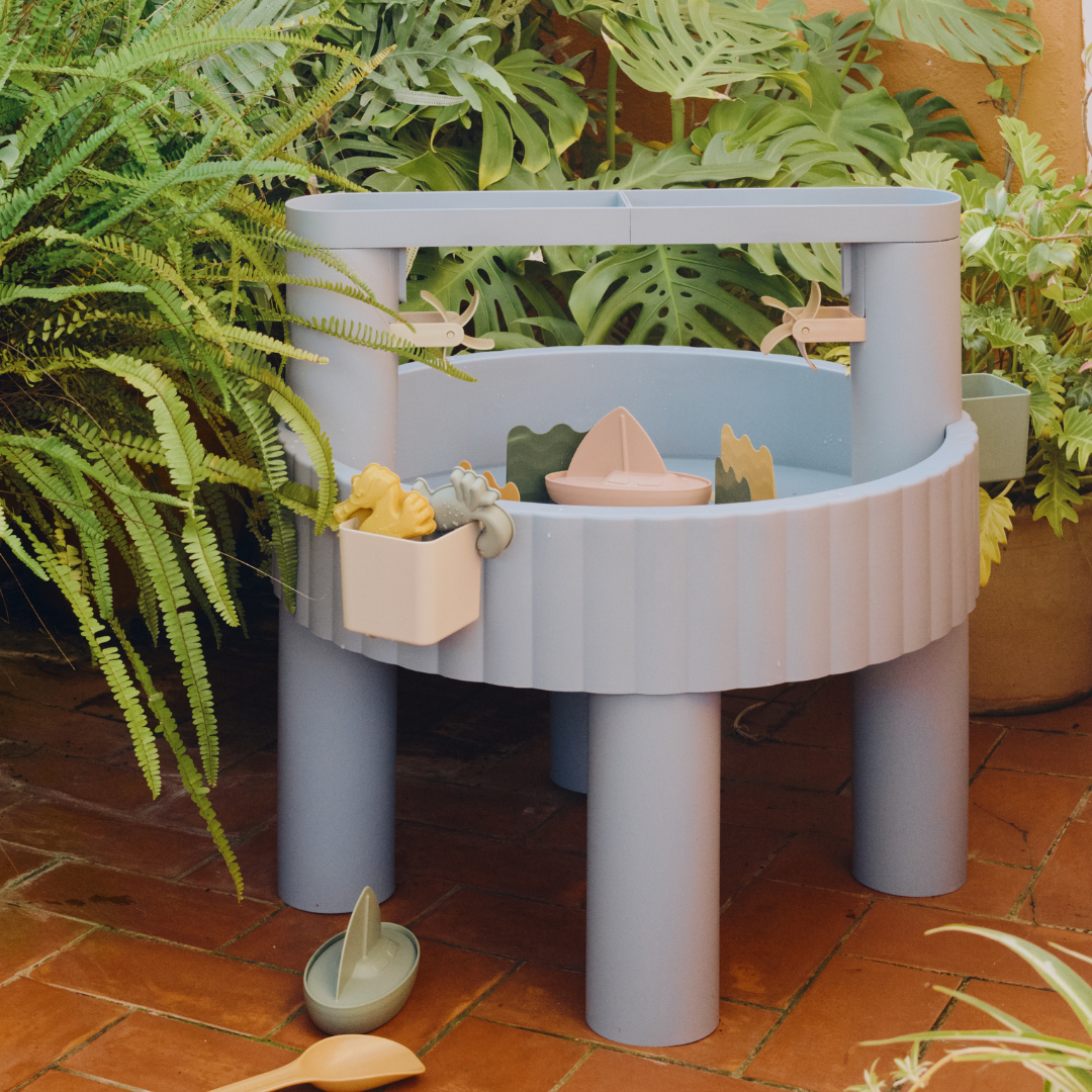 Kék Liewood Sepp homokozó és vízes játékasztal kültéren növények között