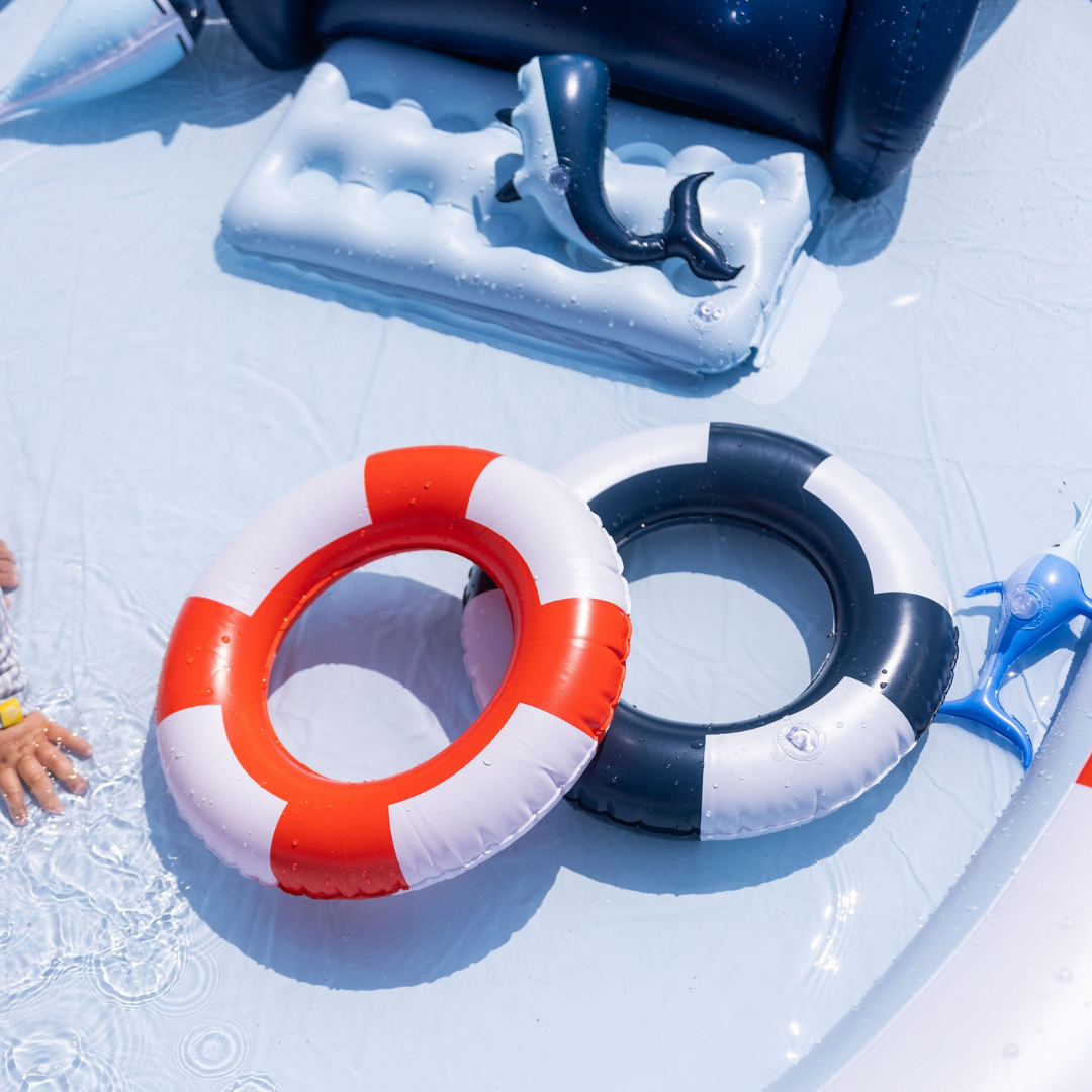 Piros-fehér és sötétkék-fehér apró felfújható úszógumik a tengerész medencében.