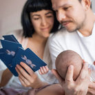 Anya és apa az újszülött babával a Modern Goddess apakártyákat nézik.