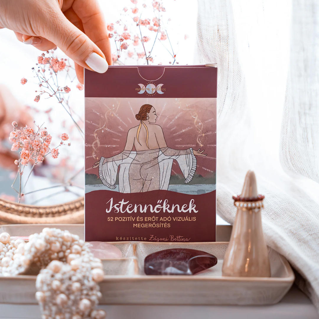 Modern Goddess Istennőknek kártyacsomag doboza egy tálcán, gyöngyökkel és ásványokkal körülvéve.
