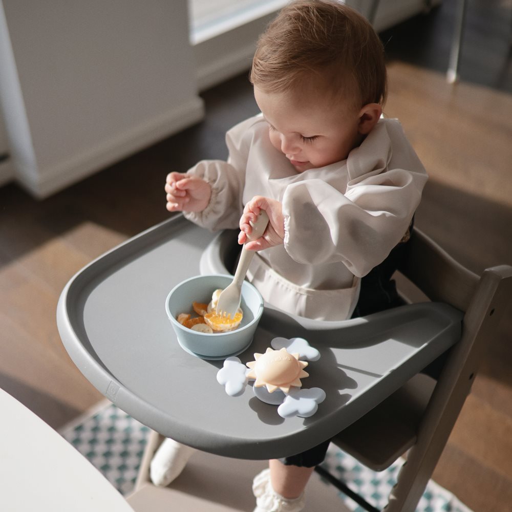 Kisbaba evés közben napocskás tapadókorongos pörgettyűvel játszik