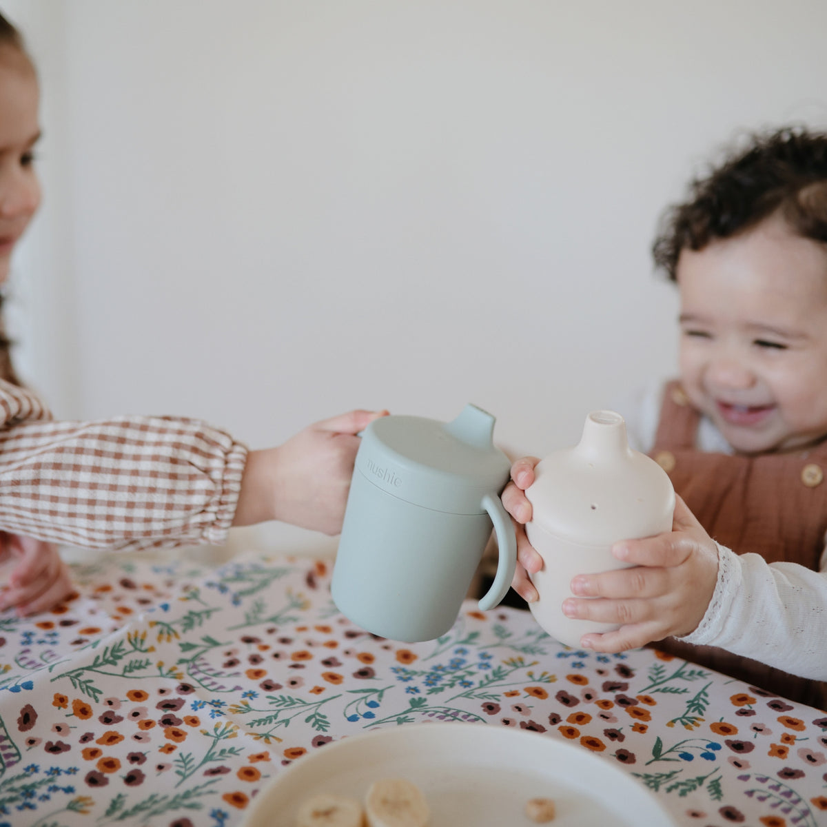 Gyerekek koccintanak az ebédlőasztalnál itatópohárral - pippadu