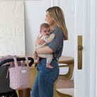 Édesanya mosolyog kisbabájával a kezében, mellette babakocsin Cherry virágos kézi táska egyszerűen rögzítve a rövid fülekkel, patentokkal