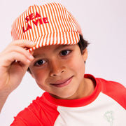 Kisfiú piros-fehér csíkos Sea La Vie baseball sapkában és hozzá illő UV-szűrős pólóban.
