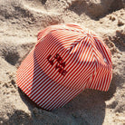 Swim Essentials csíkos gyerek baseball sapka a tengerparti homokban.