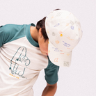 Közelkép a Swim Essentials fehér alapszínű, színes szörfös és hullám mintás gyerek baseball sapkájáról.