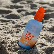 Swim Essentials SPF 50+ napvédő spray a tengerparti homokban – gyors és hatékony fényvédelem.
