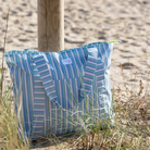 Csíkos mintás strandtáska a homokos tengerparton egy faoszlop mellett a homokban